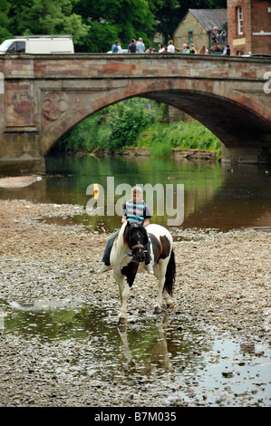 Ein Roma-junge reitet auf einem Pferd in den Fluss Eden in Appleby in Westmoreland Appleby Zigeuner Pferd Messe bareback Stockfoto