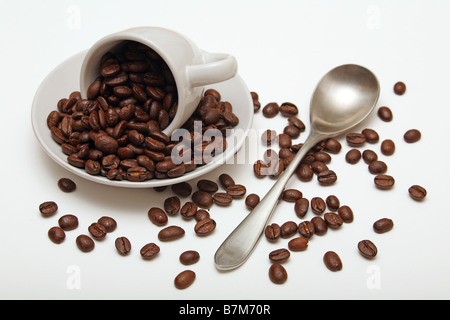 Kaffeebohnen verschüttete Tasse Löffel Untertasse auf weißem Hintergrund Stockfoto