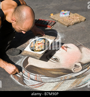 Ein männlicher Künstler zeichnen das Porträt einer Frau, die mit Kreide auf dem Bürgersteig in Florenz, Italien Stockfoto