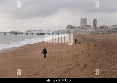 Eine Person Metalldetektor am Strand von Brighton in England an einem bewölkten Tag, nach einem Sturm. Stockfoto