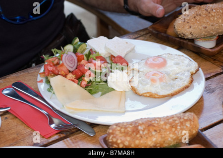 Traditionelle israelisches Frühstück mit zwei Spiegeleiern gelber Käse Salat und ein frisches Brötchen Stockfoto