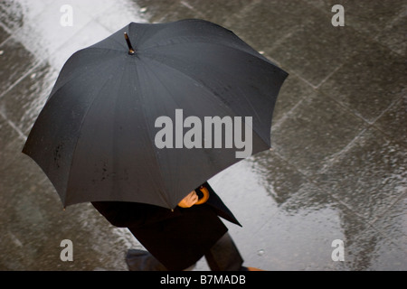Regen Sie im Londoner Finanzviertel Mann mit Regenschirm auf düsteren London morgen in der Rush hour Stockfoto