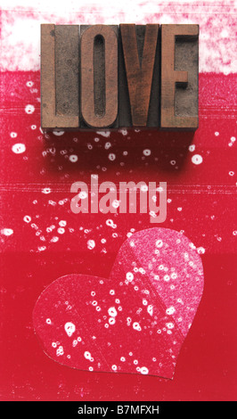 das Wort "Liebe" im alten Holz-Art auf einem fleckigen roten und weißen Hintergrund mit einer Herzform Stockfoto