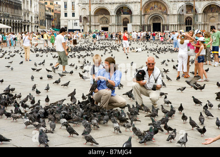 Menschen, die Tauben füttern, in Piazza San Marco Markusplatz, Venedig, Italien Stockfoto