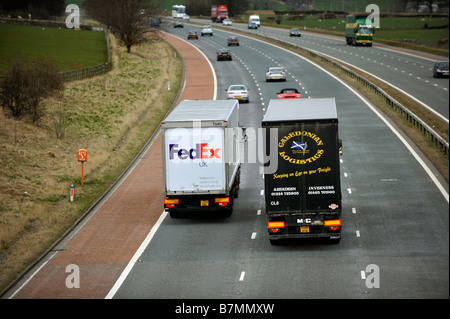 Caledonian Logistik LKW überholt einen Fed Ex-LKW Stockfoto