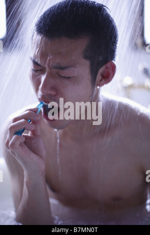 Mann, sitzen unter der Dusche, seine Zähne zu putzen Stockfoto