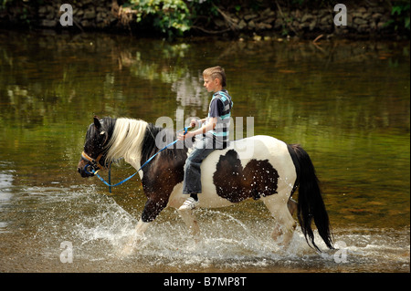 Ein Roma-junge reitet auf einem Pferd in den Fluss Eden in Appleby in Westmoreland Appleby Zigeuner Pferd Messe bareback Stockfoto