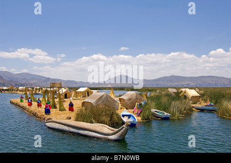 Eine traditionelle Reed-Boot und Frauen gekleidet in traditioneller Kleidung in einem von den Schilfinseln im Titicacasee. Stockfoto