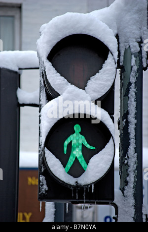 Schnee bedeckt die britische Ampel grünen Mann zeigen, erscheinen, um zu Fuß über Schnee, darauf hinweist, dass Fußgänger überqueren sollte Stockfoto