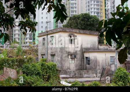 Traditionelles zweistöckiges, flaches Betondörfhaus in den New Territories Hongkong mit modernem Hochhaus im Hintergrund. Stockfoto
