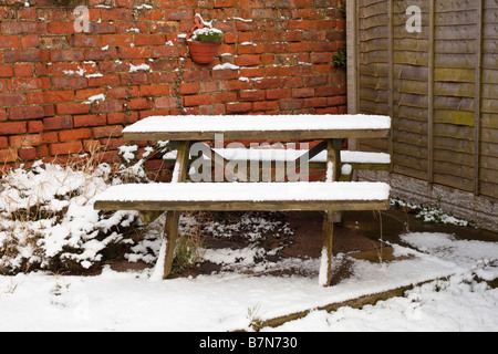 Gartentisch aus Holz oder Bank im Vereinigten Königreich Schnee im Winter überdacht Stockfoto