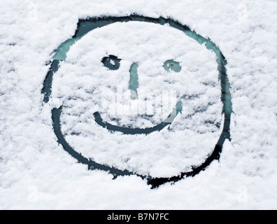 Winterschnee - Smiley-Gesicht gezeichnet im Neuschnee auf einer Auto-Windschutzscheibe Stockfoto