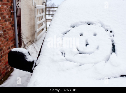 Smiley-Gesicht gezeichnet im Neuschnee auf einer Auto-Windschutzscheibe Stockfoto