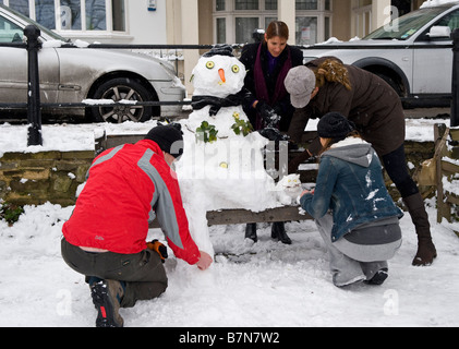 Letzten Schliff auf einem Schneemann und Snowcat sitzt auf einer Parkbank Stockfoto