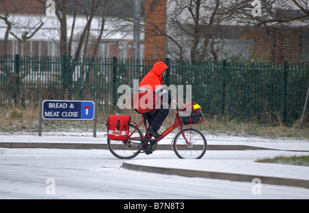 Postbote auf Fahrrad im Schnee, Warwick, Warwickshire, England, UK Stockfoto