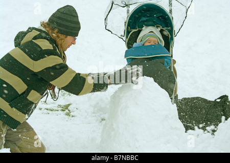 Vater Mann Person für Tochter In ihrem Kinderwagen einen Schneemann bauen Stockfoto