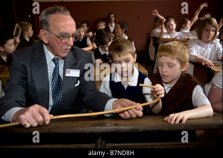 Kinder Experince Leben in einer viktorianischen Schule.  Ein älterer Mann zeigen zwei jungen einen Stock. Stockfoto