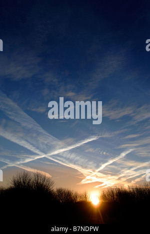 KONDENSSTREIFEN BILDEN EIN INTERESSANTES MUSTER ÜBER DEN MORGENHIMMEL IN WILTSHIRE UK Stockfoto