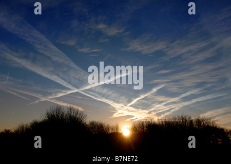 KONDENSSTREIFEN BILDEN EIN INTERESSANTES MUSTER ÜBER DEN MORGENHIMMEL IN WILTSHIRE UK Stockfoto