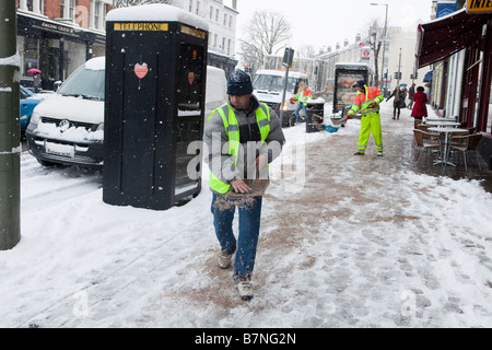 Barnet Borough Council Arbeiter zu verbreiten, Splitt und Salz auf dem Bürgersteig in der Nähe von East Finchley Underground Station Stockfoto