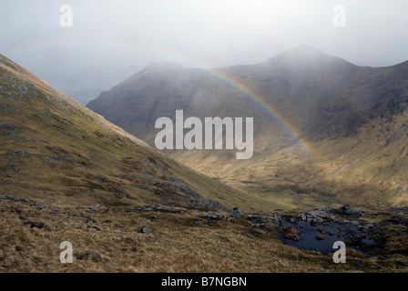 Regenbogen im Lairig Gartain als Schneesturm übergeht Buachaille Etive Mor Ridge, Glen Coe, Lochaber, Schottland, Mai Stockfoto