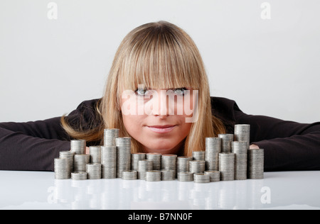 Junge Frau hinter gestapelten Münzen Stockfoto