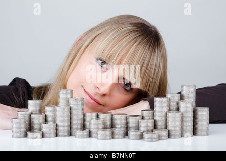 Junge Frau hinter gestapelten Münzen Stockfoto