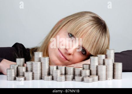 Junge Frau hinter gestapelten Münzen Stockfoto