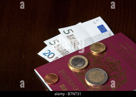 Euro-Banknoten und Münzen in einen britischen Pass. Stockfoto