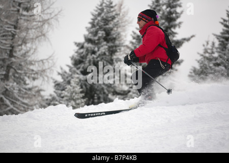 Männlichen Skifahrer trägt eine rote Jacke Skifahren schnell auf einem Berghang im Pulverschnee auf Piste in Österreichische Alpen. Österreich, Europa. Stockfoto