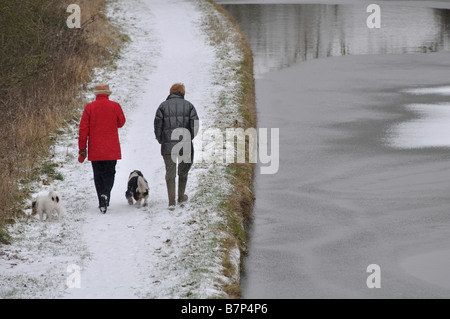 Hund Spaziergänger durch Grand Union Canal im Winter, Warwickshire, England, UK Stockfoto