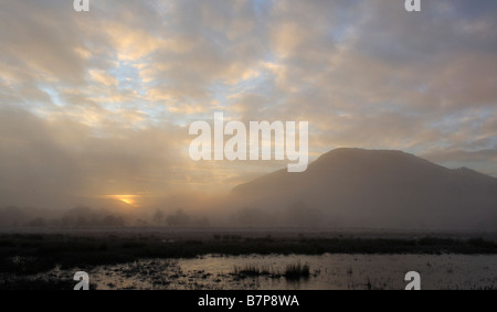 Trübe Aussicht auf einem entfernten Hügel als späte Sonne glänzt durch steigende Nebel an einem Winternachmittag in der Nähe von Killin Perthshire Schottland, Vereinigtes Königreich Stockfoto