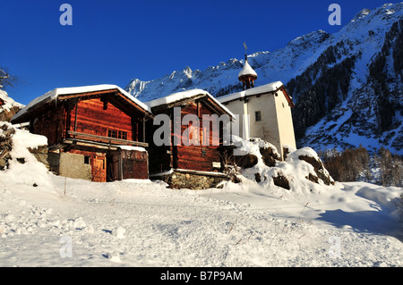 zwei alte Holz-Hütten und eine Kapelle in den Schweizer Alpen mit einer Schicht Neuschnee Stockfoto