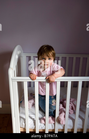 Ein elf Monate altes Baby Mädchen aufsteht in ihrem Kinderbett Stockfoto