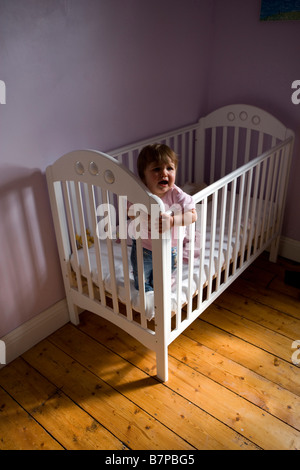 Ein Mädchen setzt sich in ihr Bett und weint Stockfoto