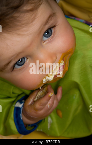 Ein kleines Mädchen mit der Nahrung in den Mund... Stockfoto