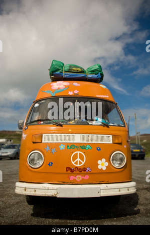 Orangefarbener, individueller Wohnwagen aus den 70er Jahren, beladen mit Gepäck auf dem Dach vor einem blauen Himmel. UK Stockfoto