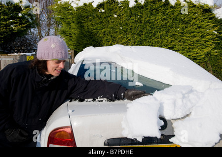 Frau ihr Schnee von ihrem Auto Reinigung Stockfoto