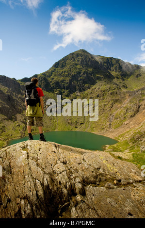 Gipfel des Mount Snowdon mit männlichem Wanderer im Vordergrund, der auf den Gipfel blickt. Stockfoto