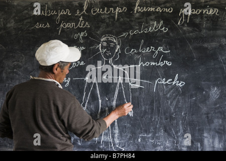 Der Lehrer schreibt an die Tafel in der kleinen Grundschule in Q'eros Spanisch Unterricht. Stockfoto