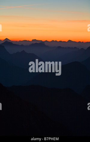 Julischen Alpen gesehen von Mangrt in Slowenien dunklen Bergen in Vordergrund mit reichen orange Sonnenuntergang zum Horizont und vor Stockfoto