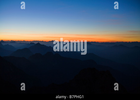 Julischen Alpen gesehen von Mangrt in Slowenien dunklen Bergen in Vordergrund mit reichen orange Sonnenuntergang zum Horizont und vor Stockfoto