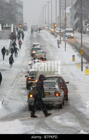 Linien des Autos und Fußgänger kämpfen zu einem schneebedeckten Hügel während der morgendlichen Rushhour nach starkem Schneefall erklimmen. Stockfoto