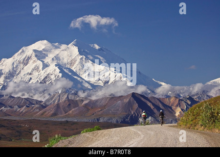 Zwei Frauen fahren Fahrräder über Thorofare Pass mit Mt. McKinley im Hintergrund im Denali-Nationalpark, Alaska Stockfoto