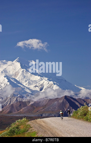 Zwei Frauen fahren Fahrräder über Thorofare Pass mit Mt. McKinley im Hintergrund im Denali-Nationalpark, Alaska Stockfoto