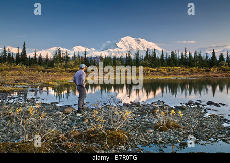 Mann steht neben einem kleinen See mit Mt. McKinley und die Alaska Range im Hintergrund im Denali-Nationalpark, Alaska Stockfoto