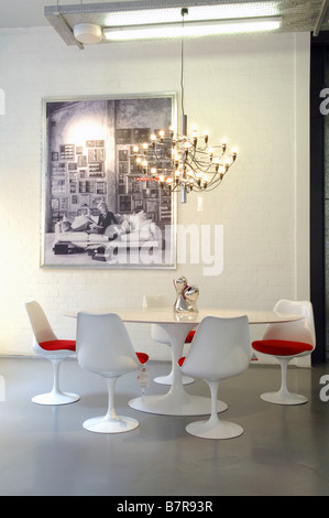 Weißer Tisch, Stühlen mit rotem Sitzkissen und ein schwarz-weißes Bild auf die Wand in einem Designer Möbel speichern. (Bild auf der Wand hinter.) Stockfoto