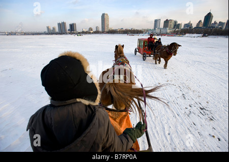 Pferdekutschen tragen Leute und Touristen über den zugefrorenen Fluss Songhua-Fluss im nördlichen China Harbin im Winter 2009 Stockfoto