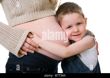 Kleiner Bruder niedliche kleine Junge im Gespräch mit seiner schwangeren Mutter Studio gedreht isolierten auf weißen Hintergrund Stockfoto