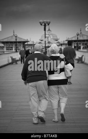 Rückansicht eines reifen kaukasischen Paares, das am Llandudno Pier entlang läuft. VEREINIGTES KÖNIGREICH Stockfoto